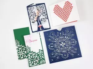 Kolekcija izrezanih vabil s cvetličnimi in srčkastimi motivi ter personalizacijo.