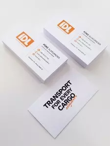 Vizitke podjetja IDL za transportne storitve z oranžnim logotipom in sloganom.