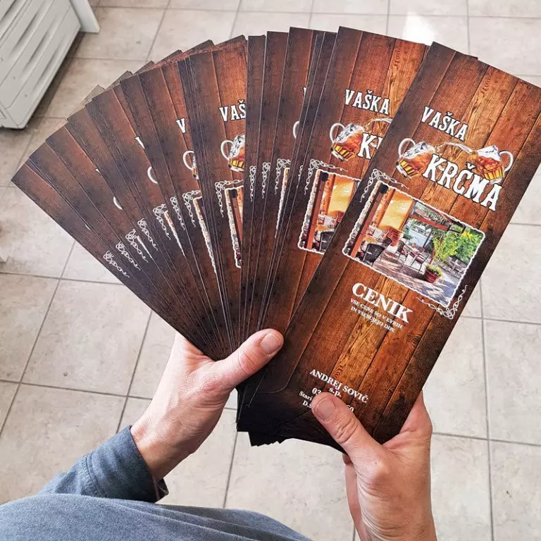 Tematski ceniki gostilne Vaška krčma z leseno podlago in pivskimi motivi, razporejeni kot